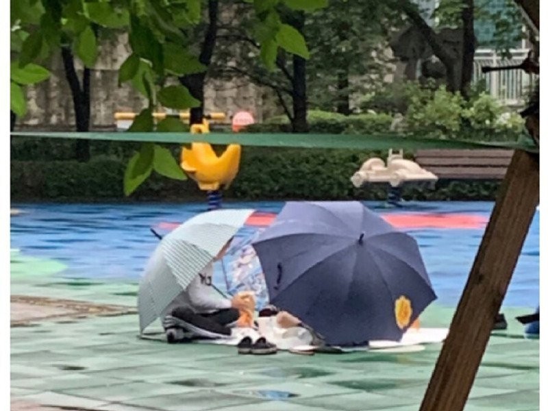 雨が降っていますが、子供たちが遊び場で遊んでいます。