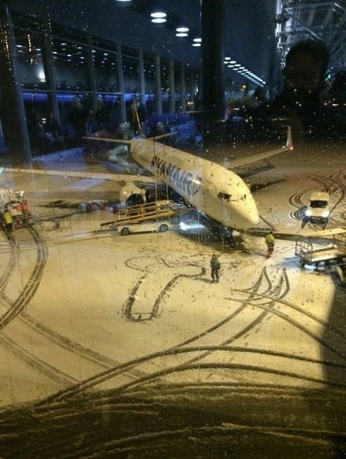 雪の空港に地上勤務スタッフがロマンチックな絵で乗客を送ります。