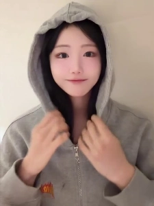 エディ・リンがグレーのパーカーのジッパーを下ろし、白いブラジャーの胸の谷間を露出