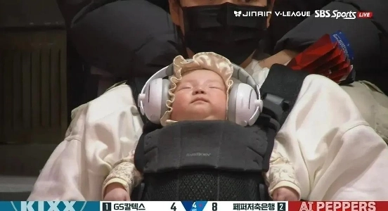 バレーボール競技場でノーカンヘッドフォンをつけて眠る観客の赤ちゃん