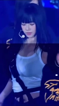 カリーナが明るさを調整します。白いタンクトップになびく黒いブラジャー。